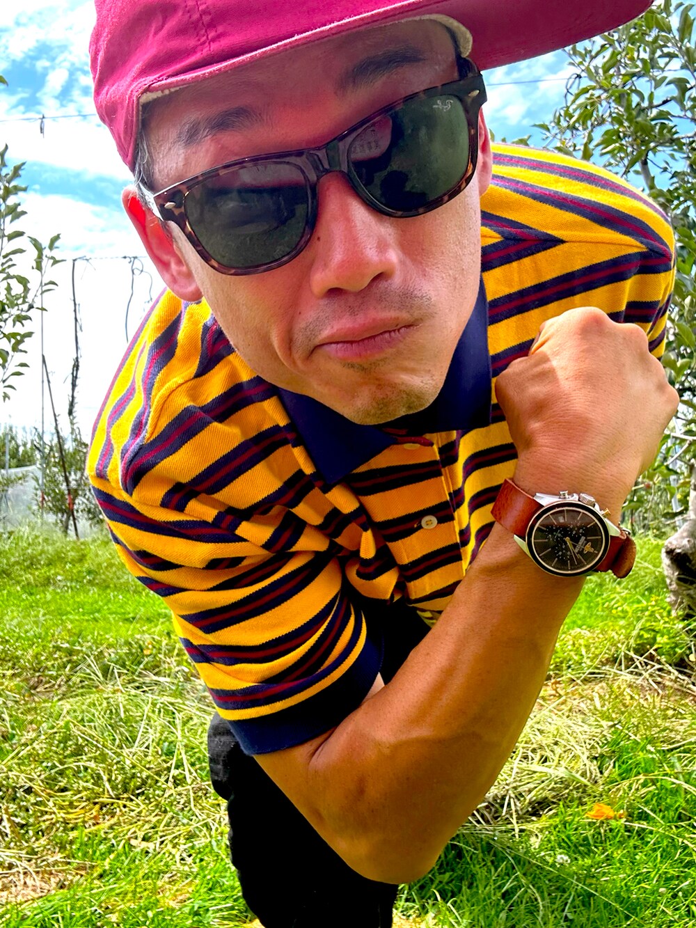 オレンジ系のポロシャツ、グリーン系のカーゴパンツ、グレー系のサンダルを着用したメンズの秋コーディネートの2枚目の写真