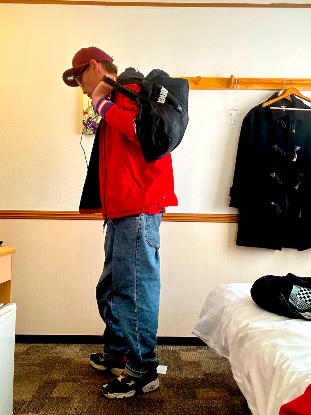 レッド系のナイロンジャケット、レッド系のその他トップス、ブルー系のデニムパンツを着用したメンズの秋コーディネートの4枚目の写真