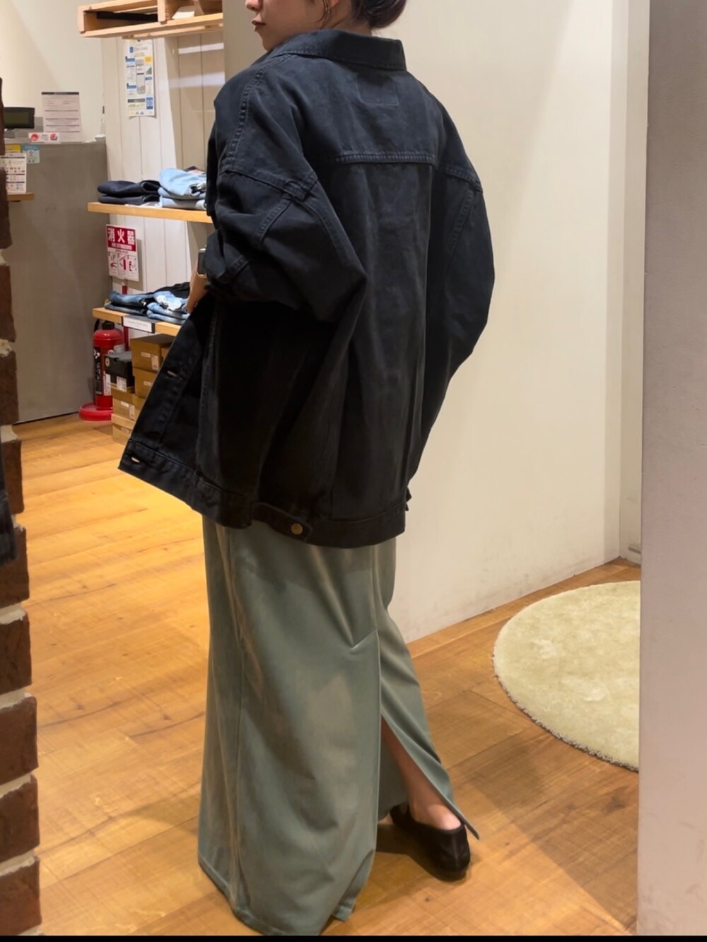 グリーン系のワンピース、ブラック系のデニムジャケット、ブラック系のメガネを着用したレディースの秋コーディネートの5枚目の写真