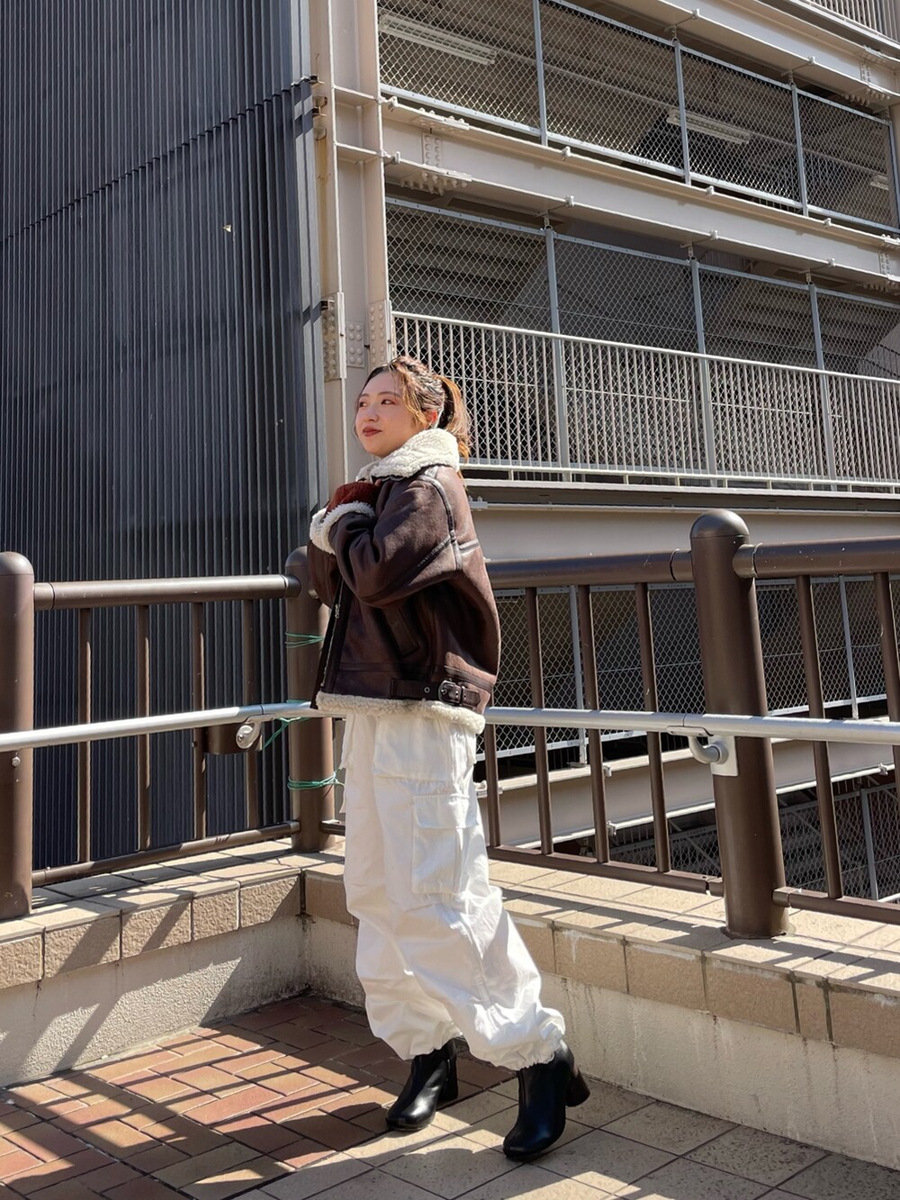 ブラウン系のムートンコート、ホワイト系のカーゴパンツ、オレンジ系のニット/セーターを着用したレディースの秋コーディネートの2枚目の写真