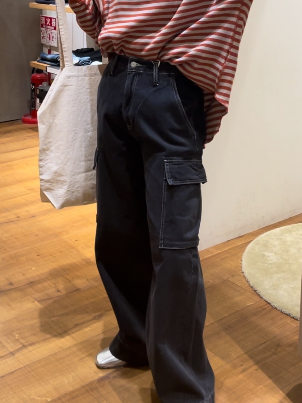 オレンジ系のTシャツ/カットソー、ブラック系のデニムパンツ、レッド系のトートバッグを着用したレディースの秋コーディネートの3枚目の写真