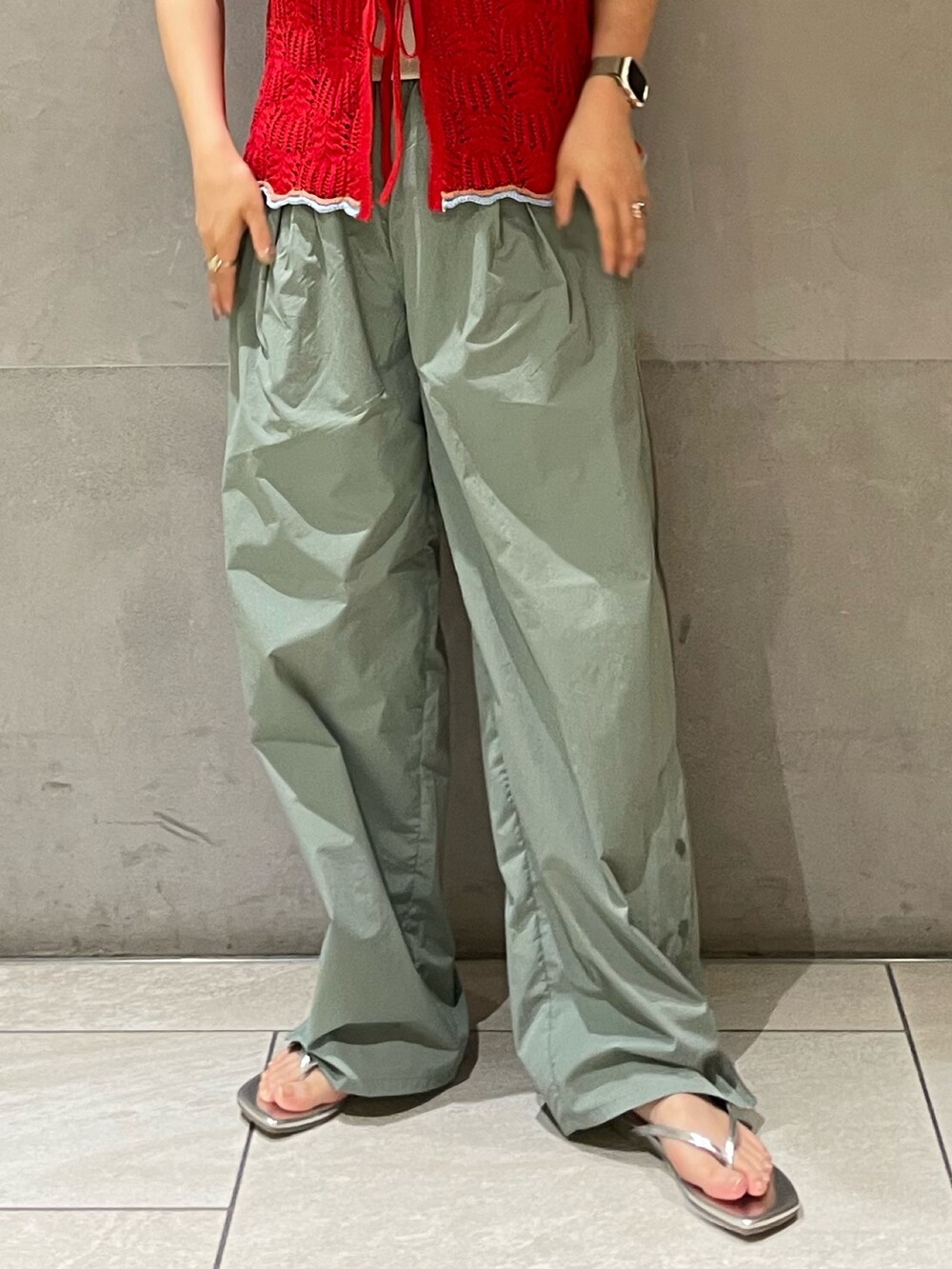 グリーン系のその他パンツ、レッド系のニット/セーター、ホワイト系のキャミソールを着用したレディースの春コーディネートの2枚目の写真