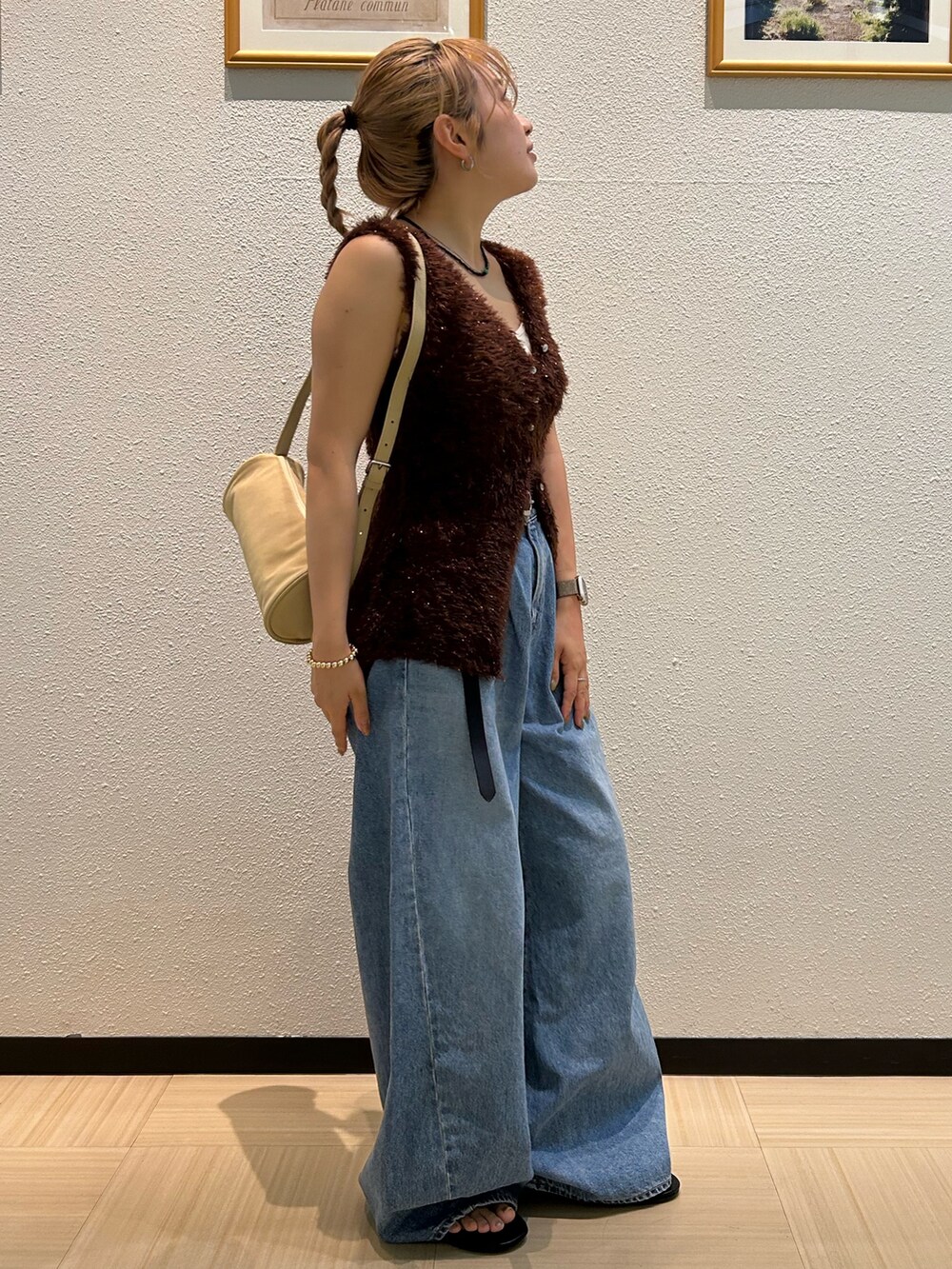 ブルー系のデニムパンツ、ブラウン系のニット/セーター、ブラック系のベルトを着用したレディースの夏コーディネートの3枚目の写真