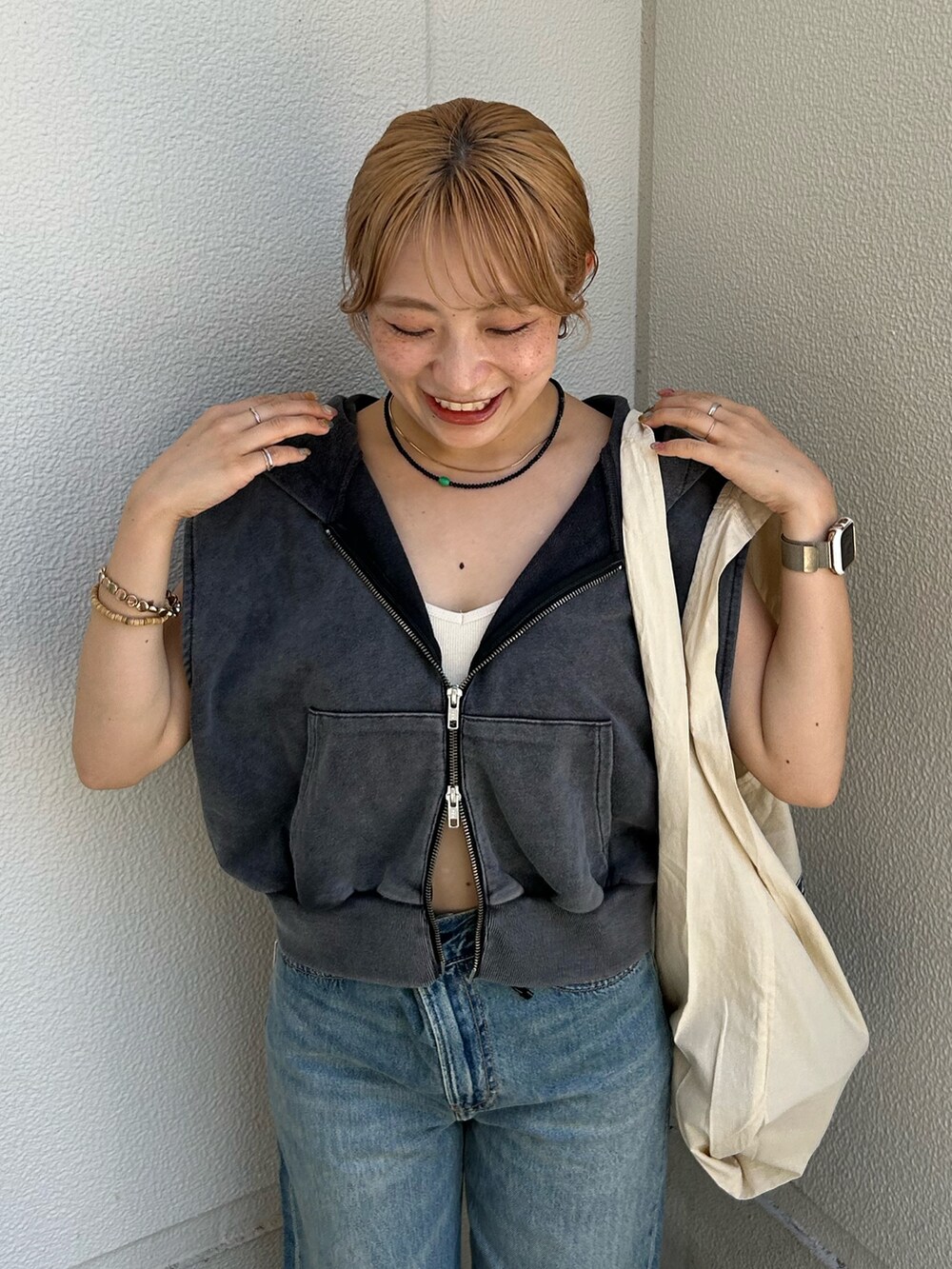 ブルー系のデニムパンツ、グレー系のパーカー、ホワイト系のトートバッグを着用したレディースの夏コーディネートの5枚目の写真