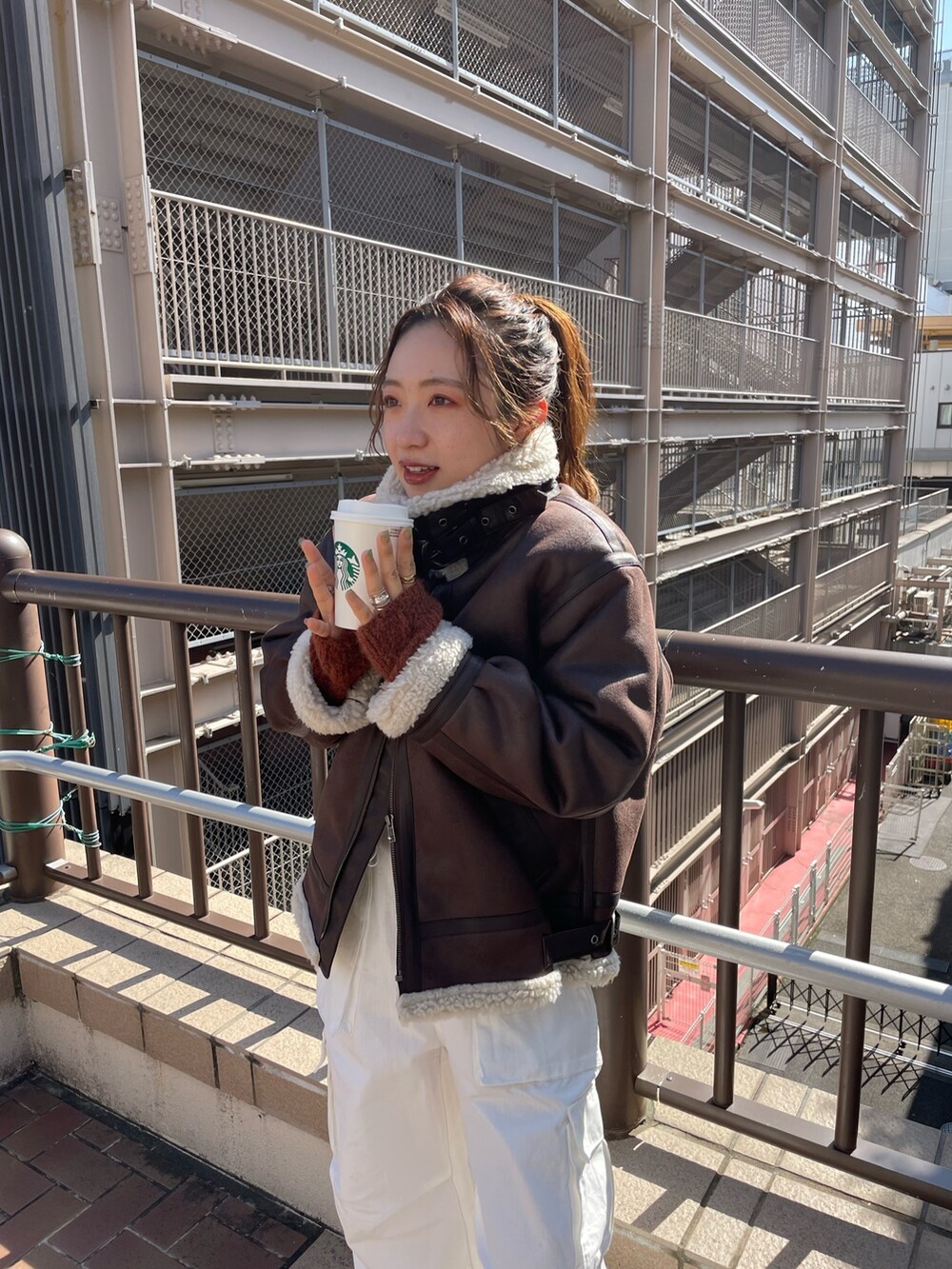 ブラウン系のムートンコート、ホワイト系のカーゴパンツ、オレンジ系のニット/セーターを着用したレディースの秋コーディネートの4枚目の写真