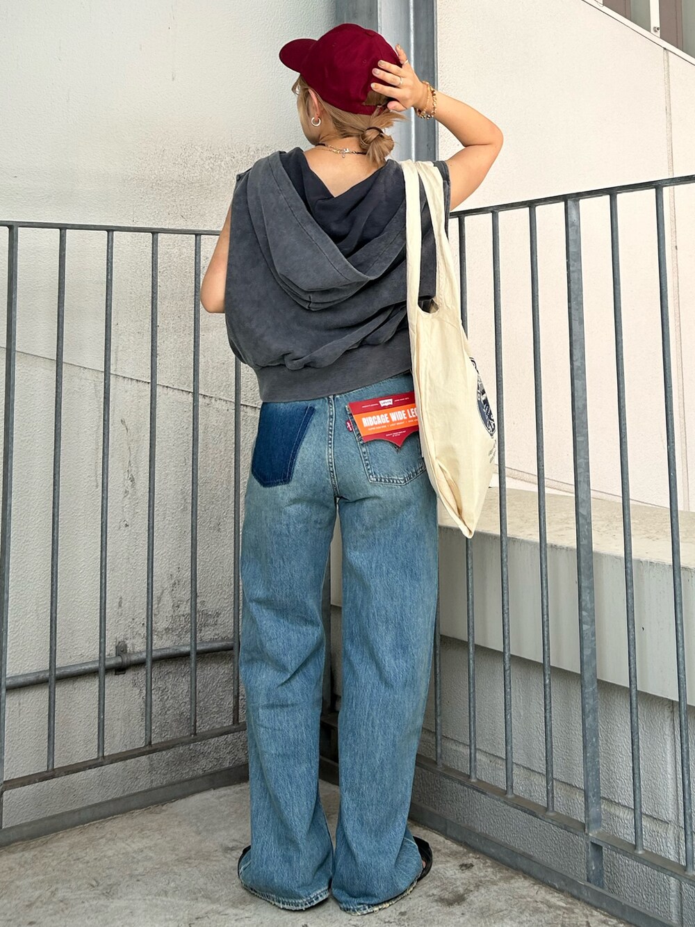 ブルー系のデニムパンツ、グレー系のパーカー、ホワイト系のトートバッグを着用したレディースの夏コーディネートの3枚目の写真