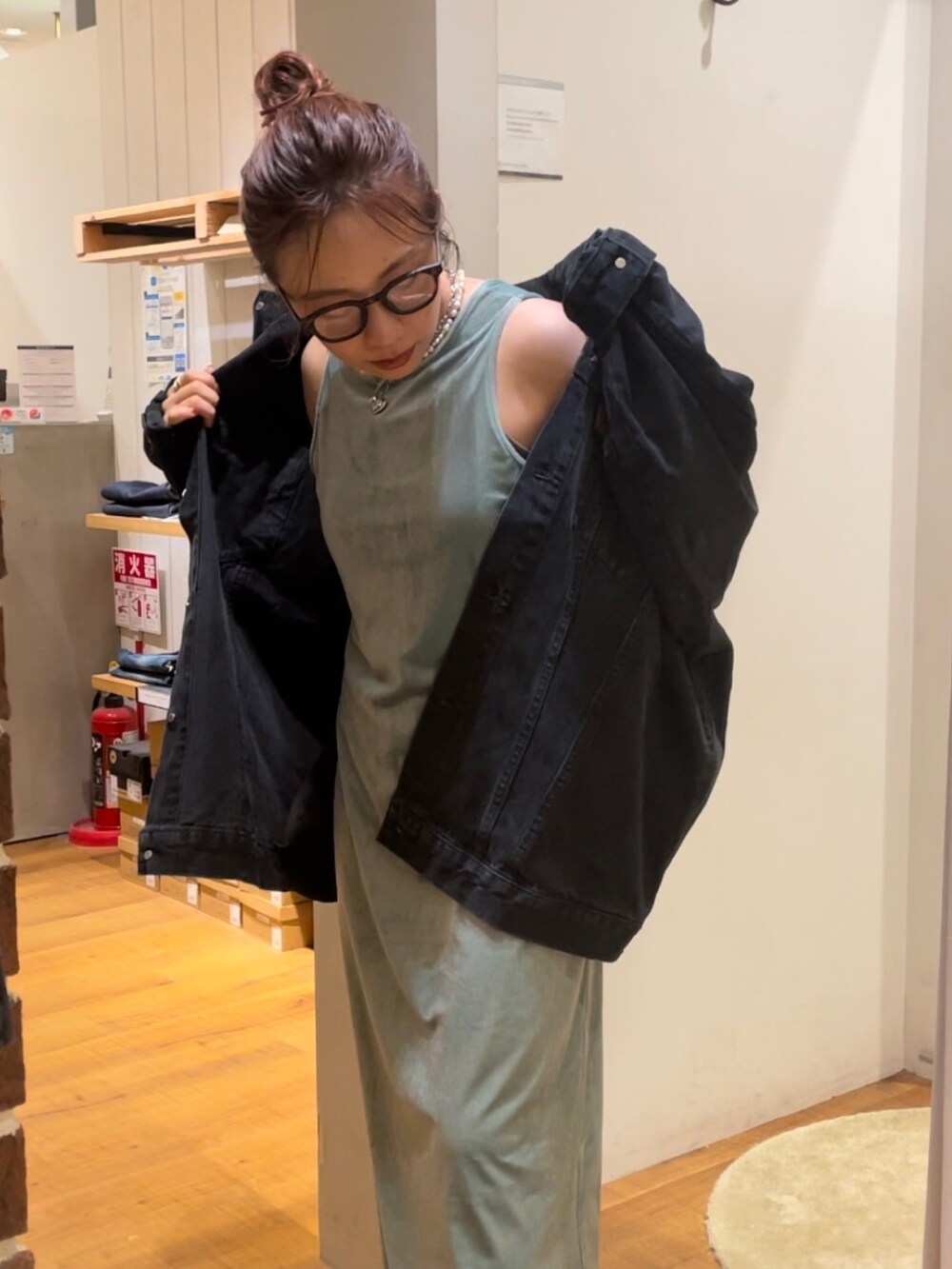 グリーン系のワンピース、ブラック系のデニムジャケット、ブラック系のメガネを着用したレディースの秋コーディネートの4枚目の写真