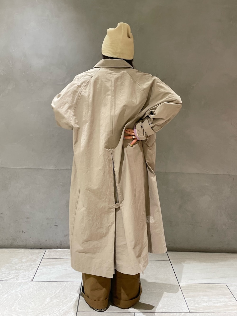 ベージュ系のステンカラーコート、イエロー系のつなぎ/オールインワン、パープル系のTシャツ/カットソーを着用したレディースの冬コーディネートの4枚目の写真