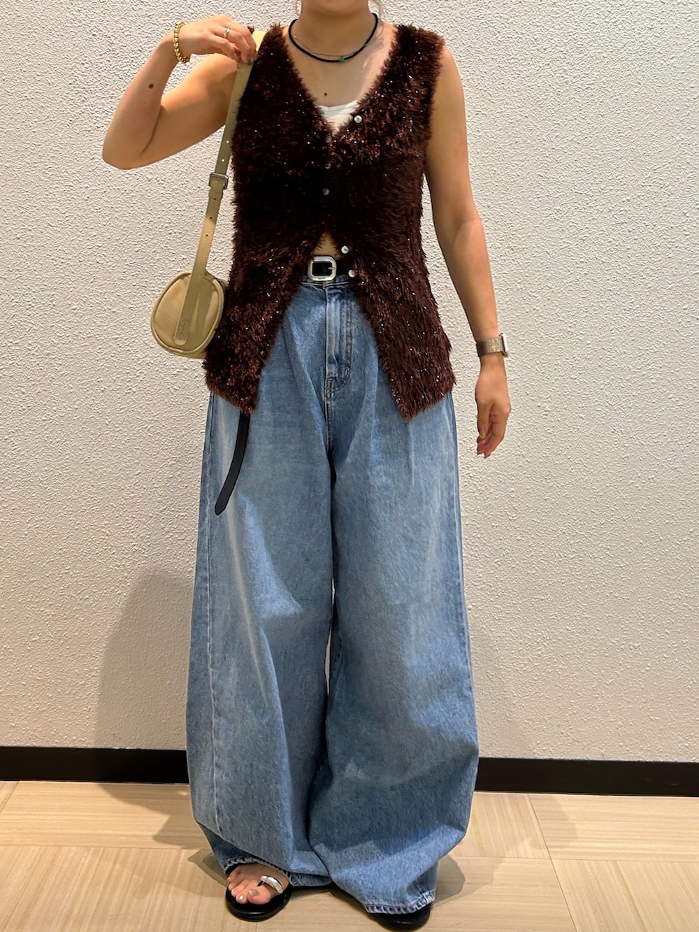 ブルー系のデニムパンツ、ブラウン系のニット/セーター、ブラック系のベルトを着用したレディースの夏コーディネートの2枚目の写真