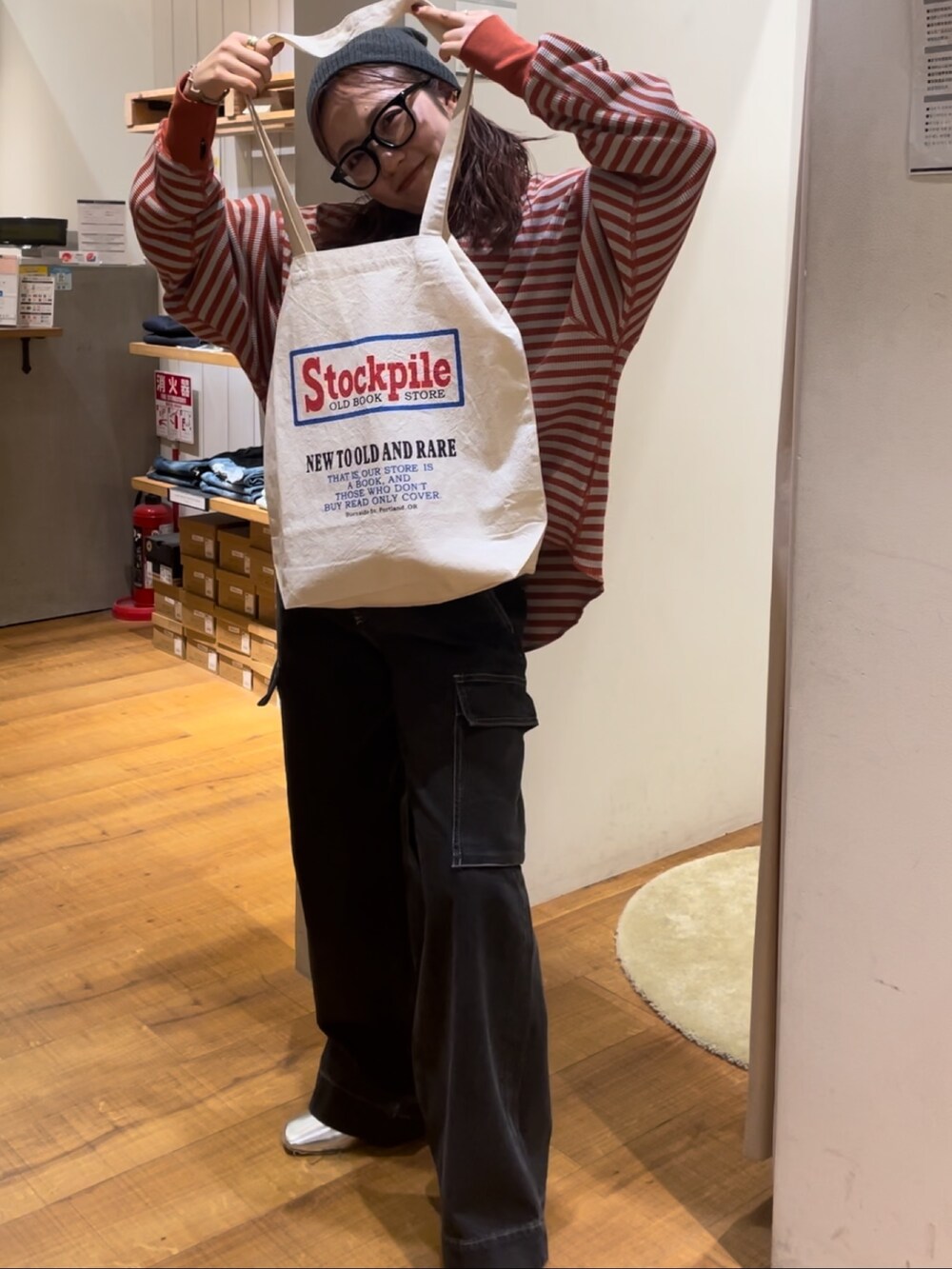 オレンジ系のTシャツ/カットソー、ブラック系のデニムパンツ、レッド系のトートバッグを着用したレディースの秋コーディネートの2枚目の写真