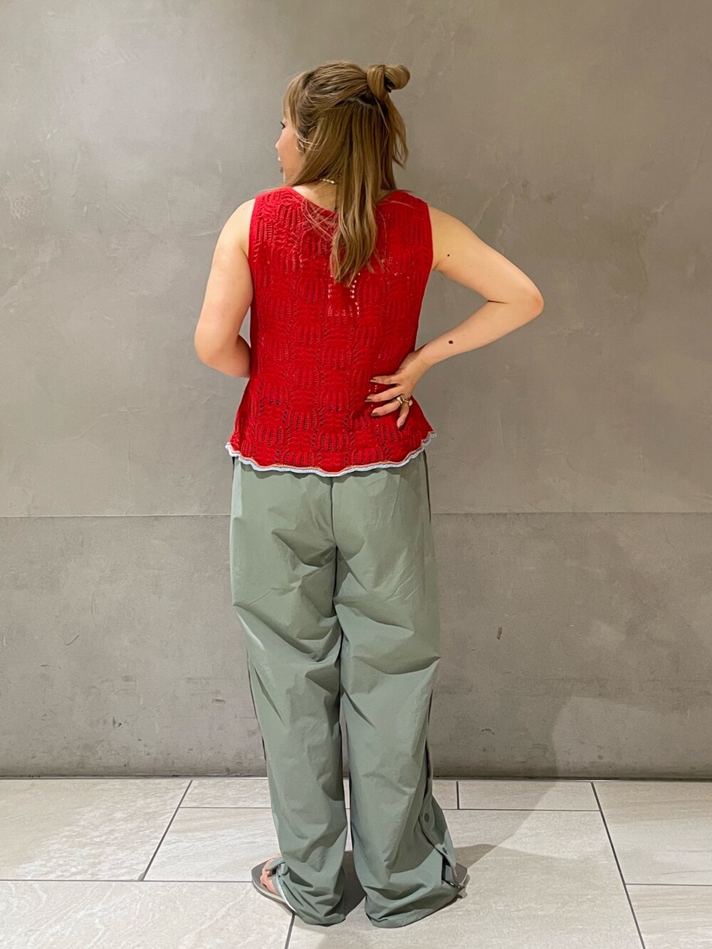 グリーン系のその他パンツ、レッド系のニット/セーター、ホワイト系のキャミソールを着用したレディースの春コーディネートの4枚目の写真