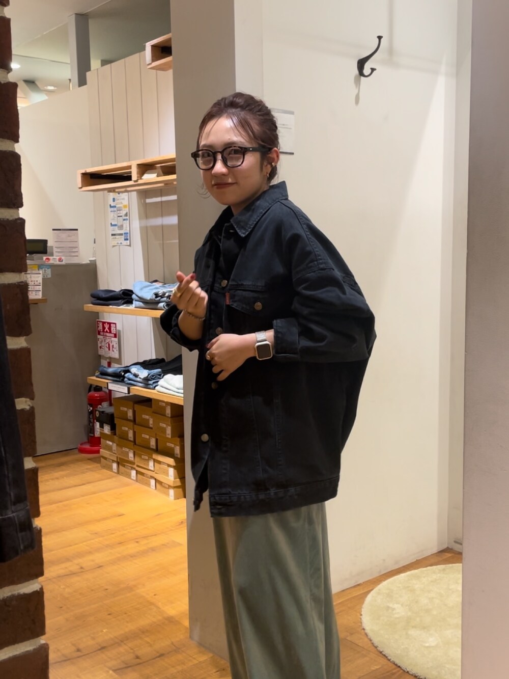 グリーン系のワンピース、ブラック系のデニムジャケット、ブラック系のメガネを着用したレディースの秋コーディネートの2枚目の写真