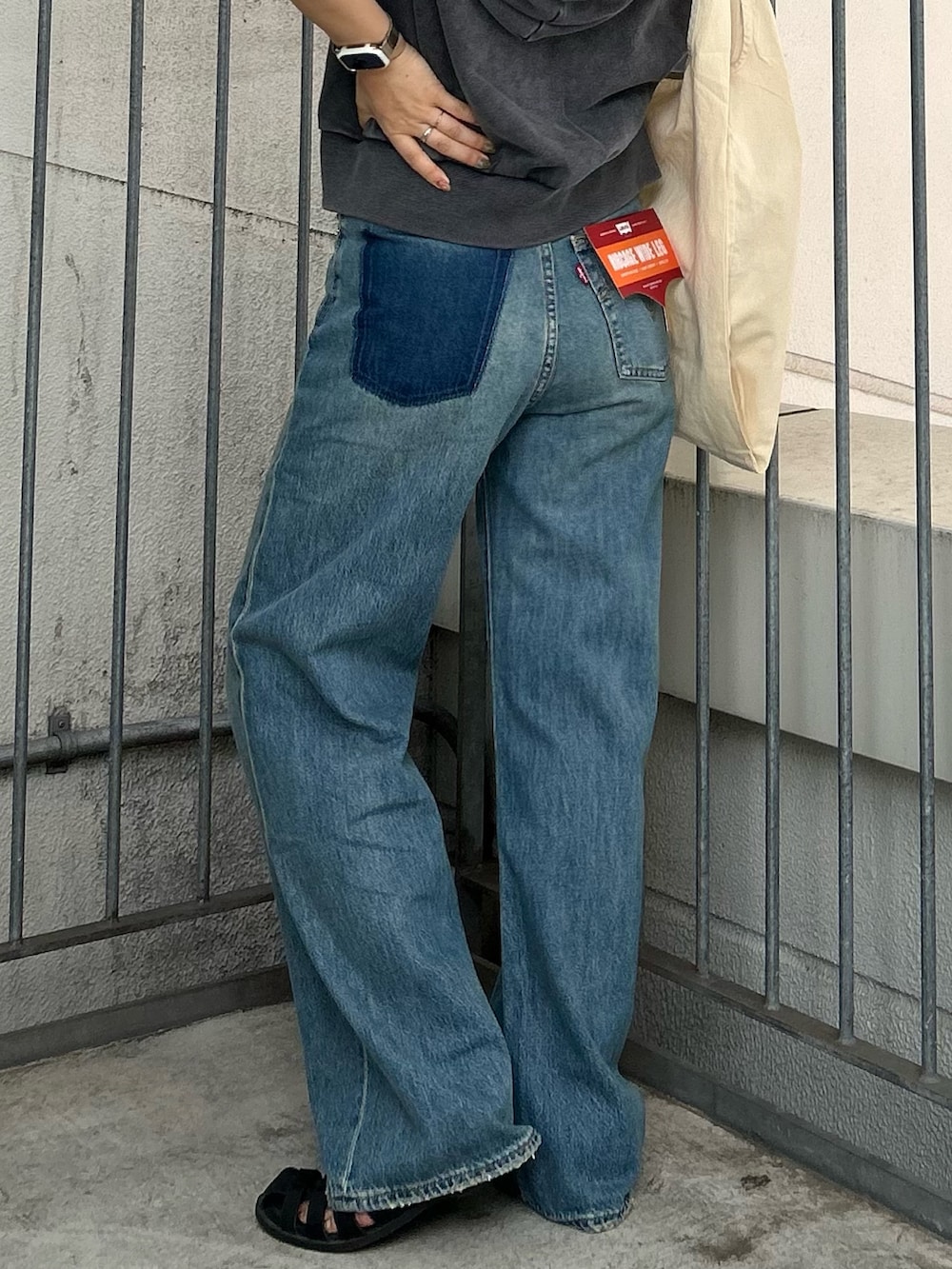 ブルー系のデニムパンツ、グレー系のパーカー、ホワイト系のトートバッグを着用したレディースの夏コーディネートの4枚目の写真