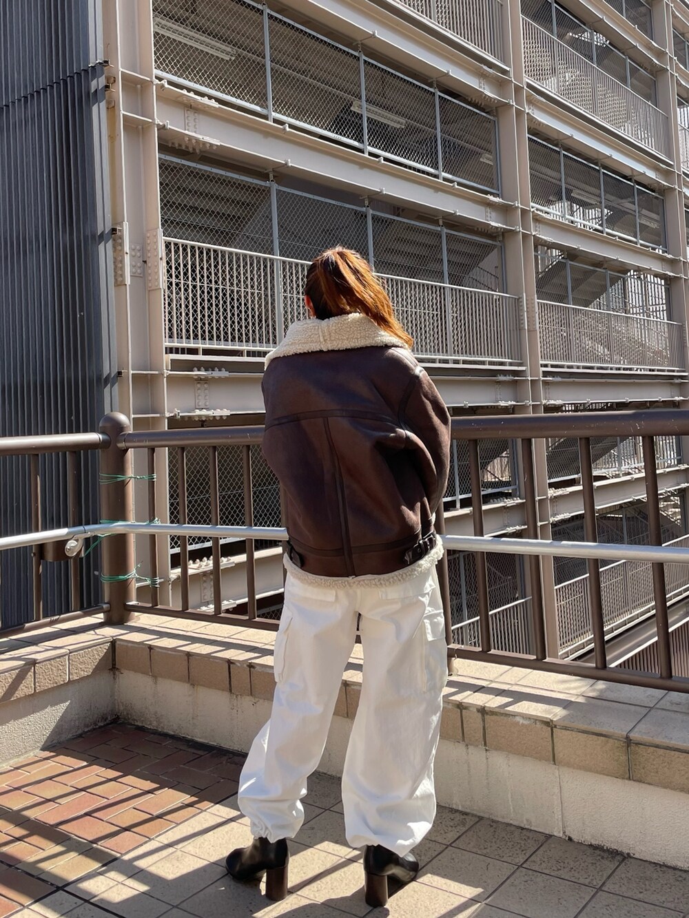 ブラウン系のムートンコート、ホワイト系のカーゴパンツ、オレンジ系のニット/セーターを着用したレディースの秋コーディネートの3枚目の写真