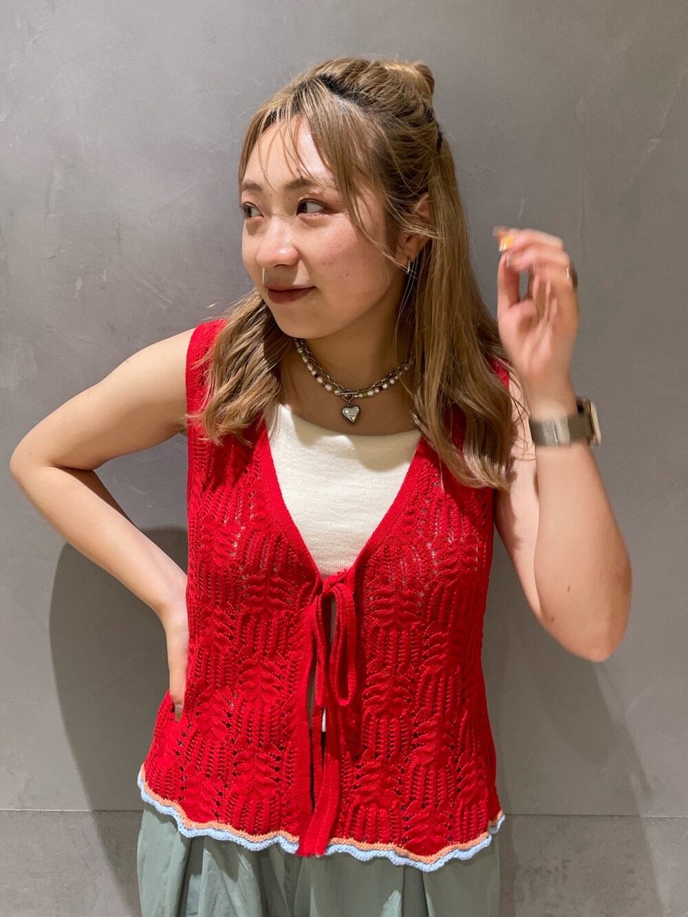 グリーン系のその他パンツ、レッド系のニット/セーター、ホワイト系のキャミソールを着用したレディースの春コーディネートの5枚目の写真