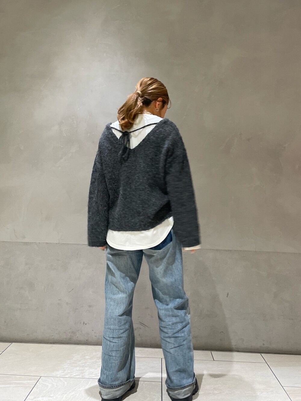 グレー系のニット/セーター、ホワイト系のTシャツ/カットソー、ブルー系のデニムパンツを着用したレディースの冬コーディネートの4枚目の写真