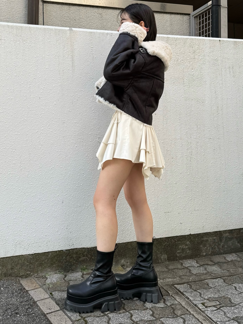 ブラック系のブーツ、ブラック系のブルゾン、ホワイト系のスカートを着用したレディースの秋コーディネートの2枚目の写真