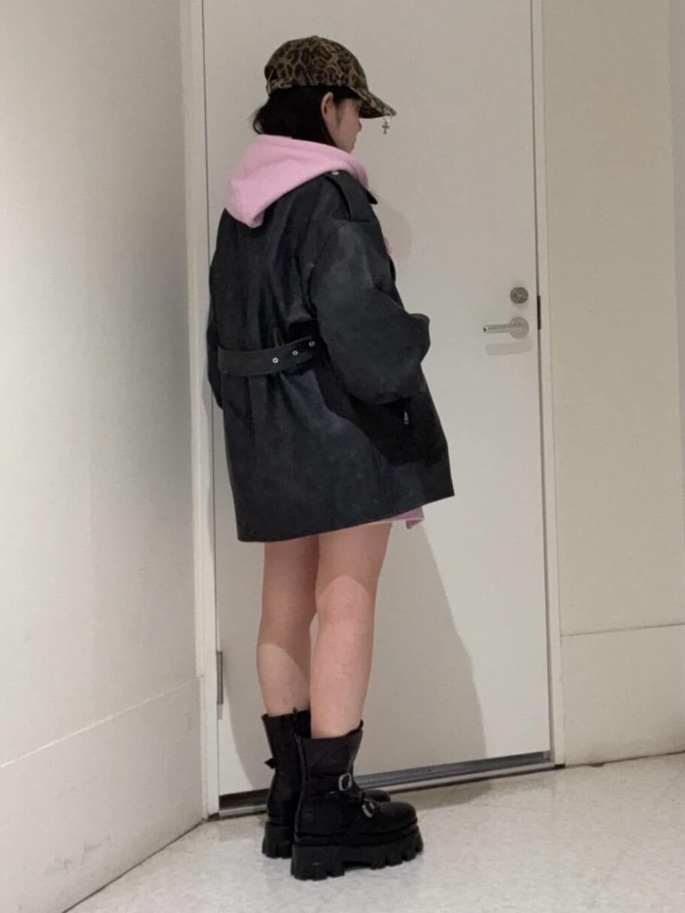 ピンク系のパーカー、ブラック系のライダースジャケット、ブラック系のブーツを着用したレディースの春コーディネートの2枚目の写真