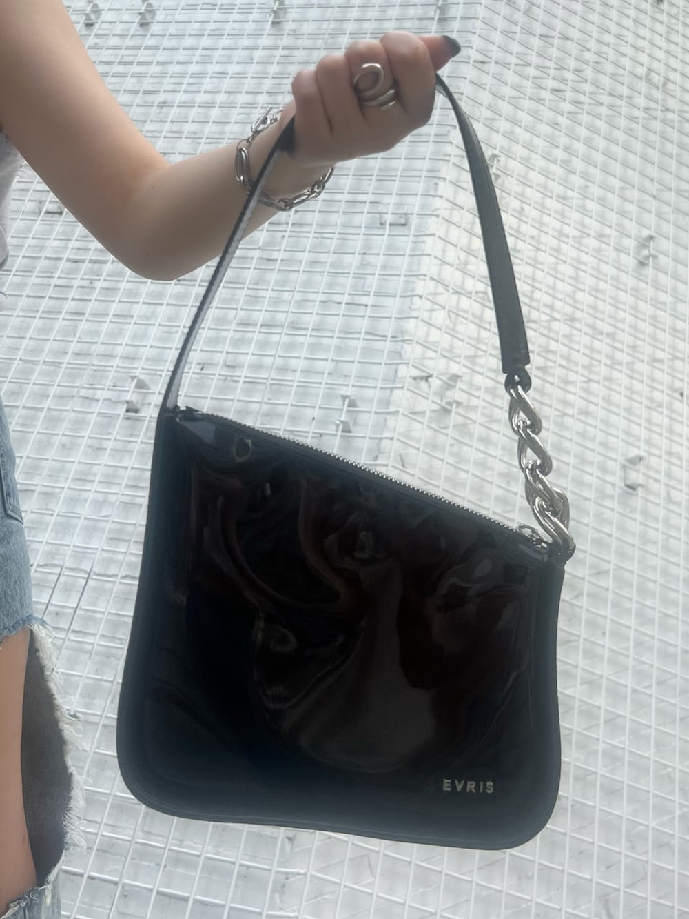 ブルー系のデニムパンツ、ブラック系のハンドバッグ、グレー系のタンクトップを着用したレディースの夏コーディネートの7枚目の写真