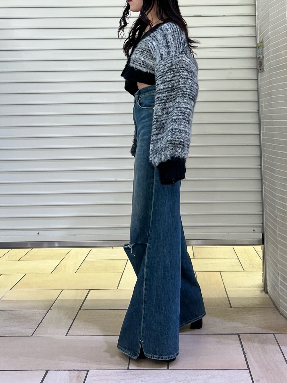 ブルー系のデニムパンツ、ブラック系のカーディガン/ボレロ、ブラック系のブーツを着用したレディースの冬コーディネートの4枚目の写真