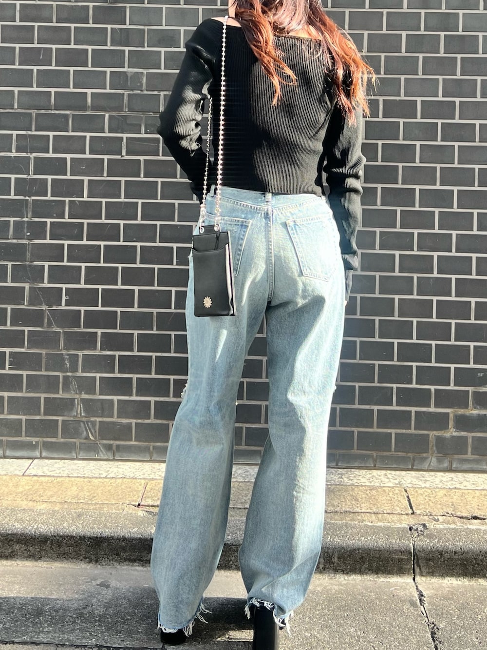 ブルー系のデニムパンツ、ブラック系のニット/セーター、ブラック系のサンダルを着用したレディースの春コーディネートの4枚目の写真