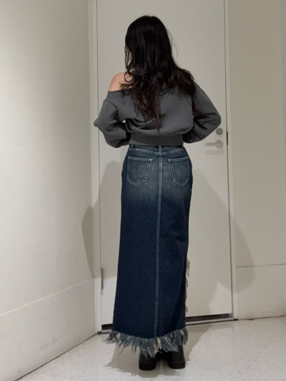 ブラック系のブーツ、ブルー系のデニムスカート、ブラック系のスウェットを着用したレディースの冬コーディネートの3枚目の写真