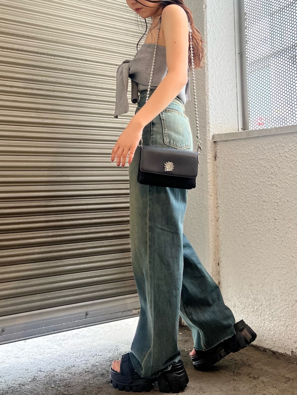 ブルー系のデニムパンツ、グレー系のキャミソール、ブラック系のショルダーバッグを着用したレディースの春コーディネートの3枚目の写真