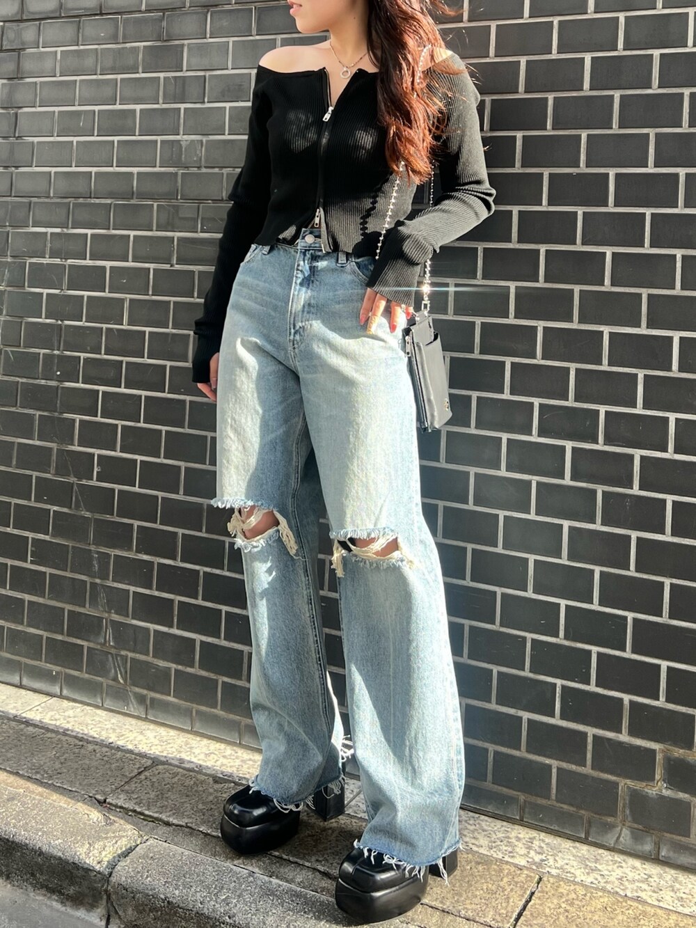 ブルー系のデニムパンツ、ブラック系のニット/セーター、ブラック系のサンダルを着用したレディースの春コーディネートの2枚目の写真