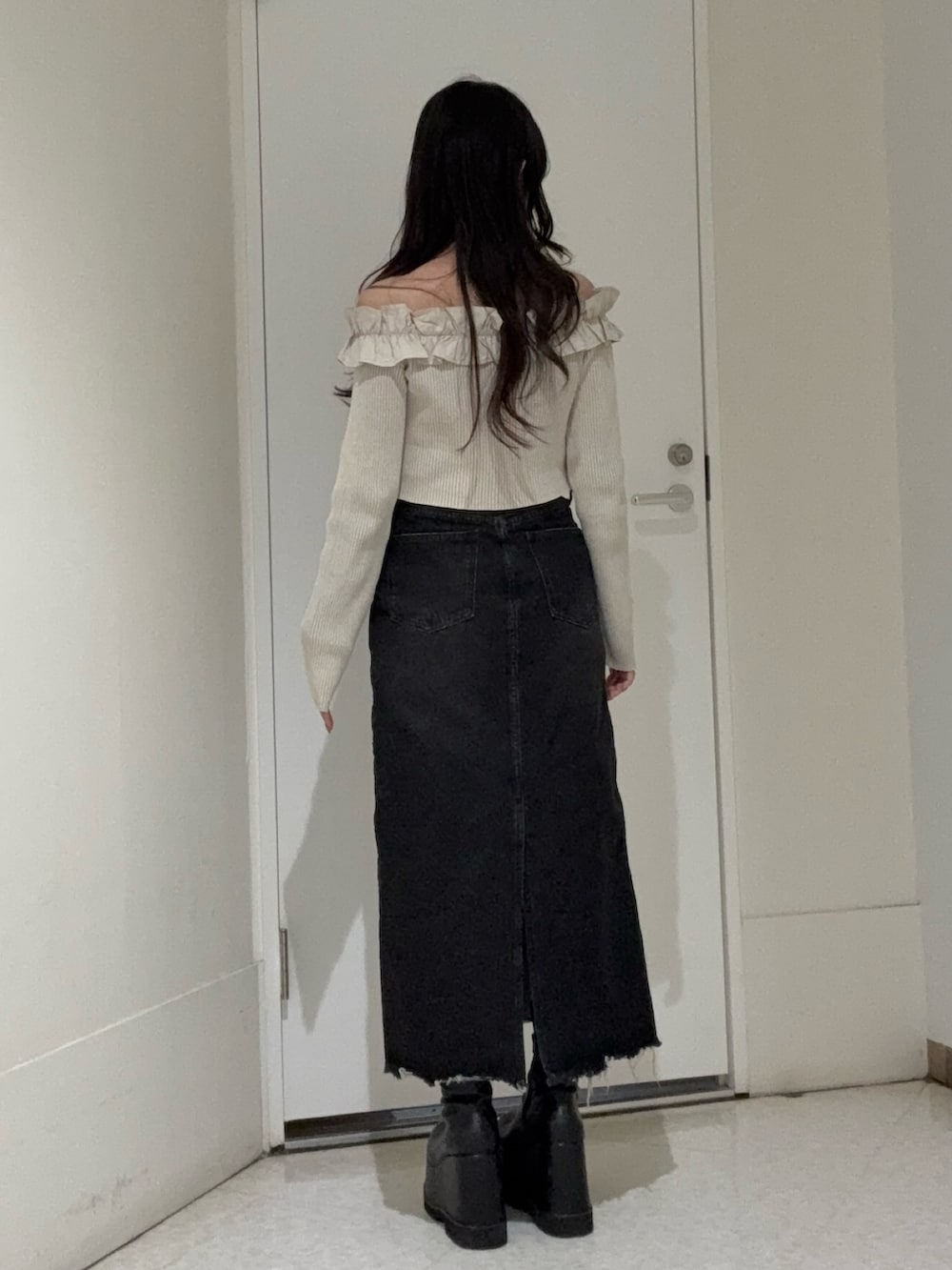 ベージュ系のニット/セーター、ブラック系のデニムスカート、ブラック系のブーツを着用したレディースの春コーディネートの3枚目の写真