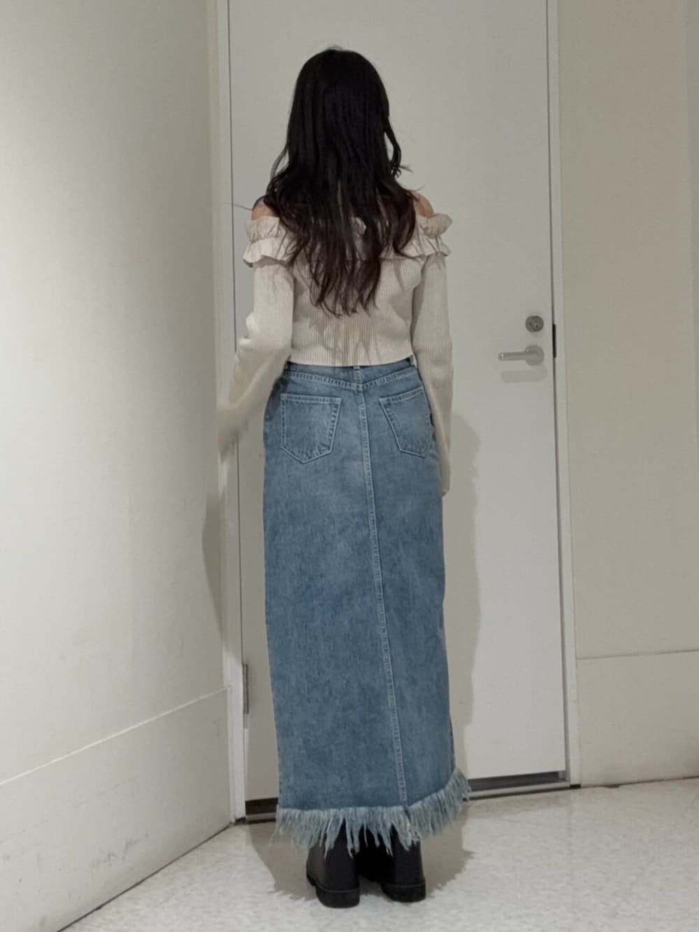 ブラック系のブーツ、ブルー系のデニムスカート、ベージュ系のニット/セーターを着用したレディースの春コーディネートの3枚目の写真