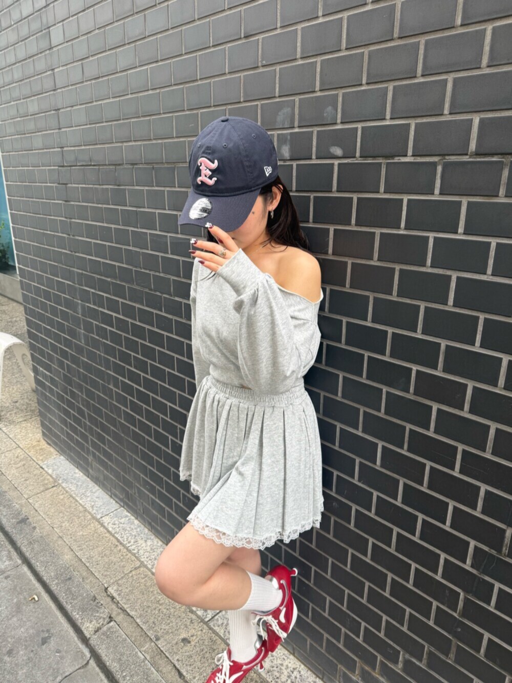 レッド系のパンプス、グレー系のスウェット、グレー系のスカートを着用したレディースの春コーディネートの7枚目の写真