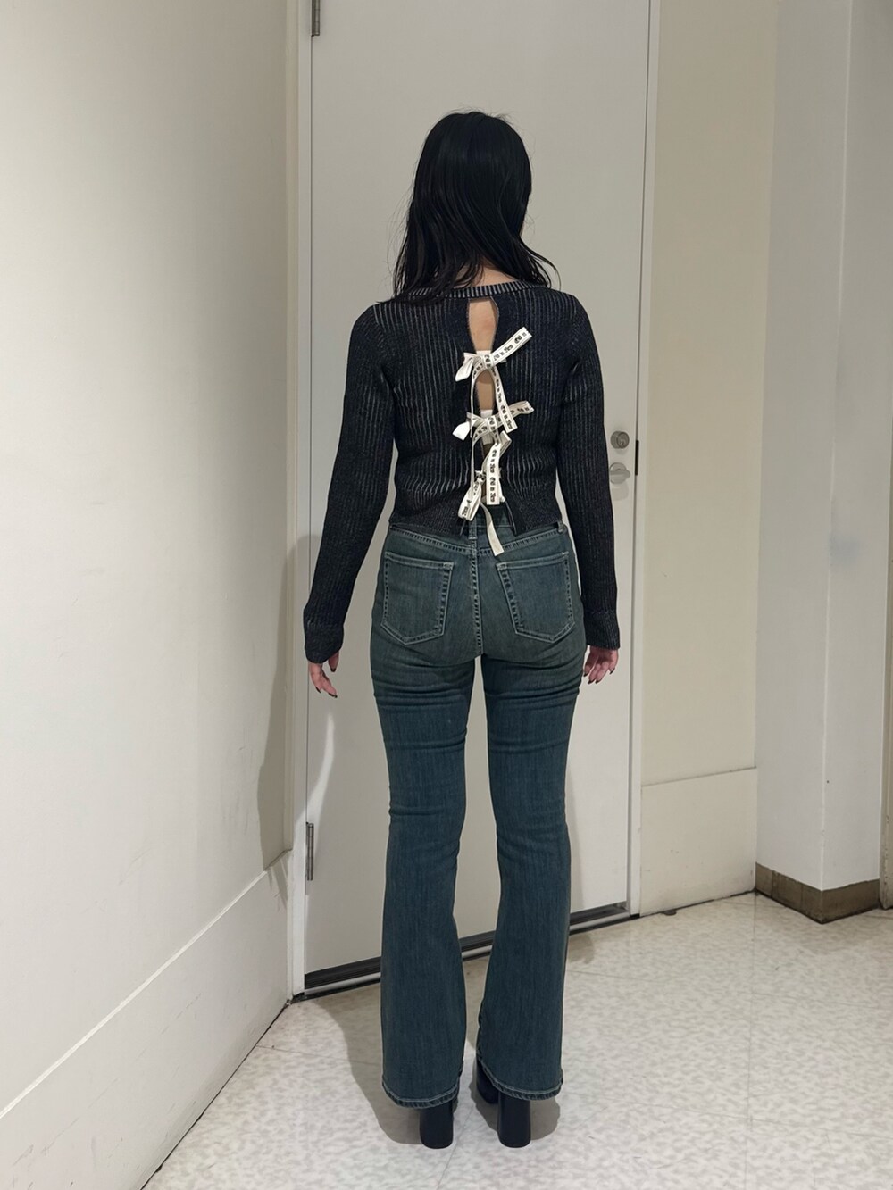 ブルー系のデニムパンツ、ブラック系のニット/セーター、ブラック系のブーツを着用したレディースの秋コーディネートの3枚目の写真
