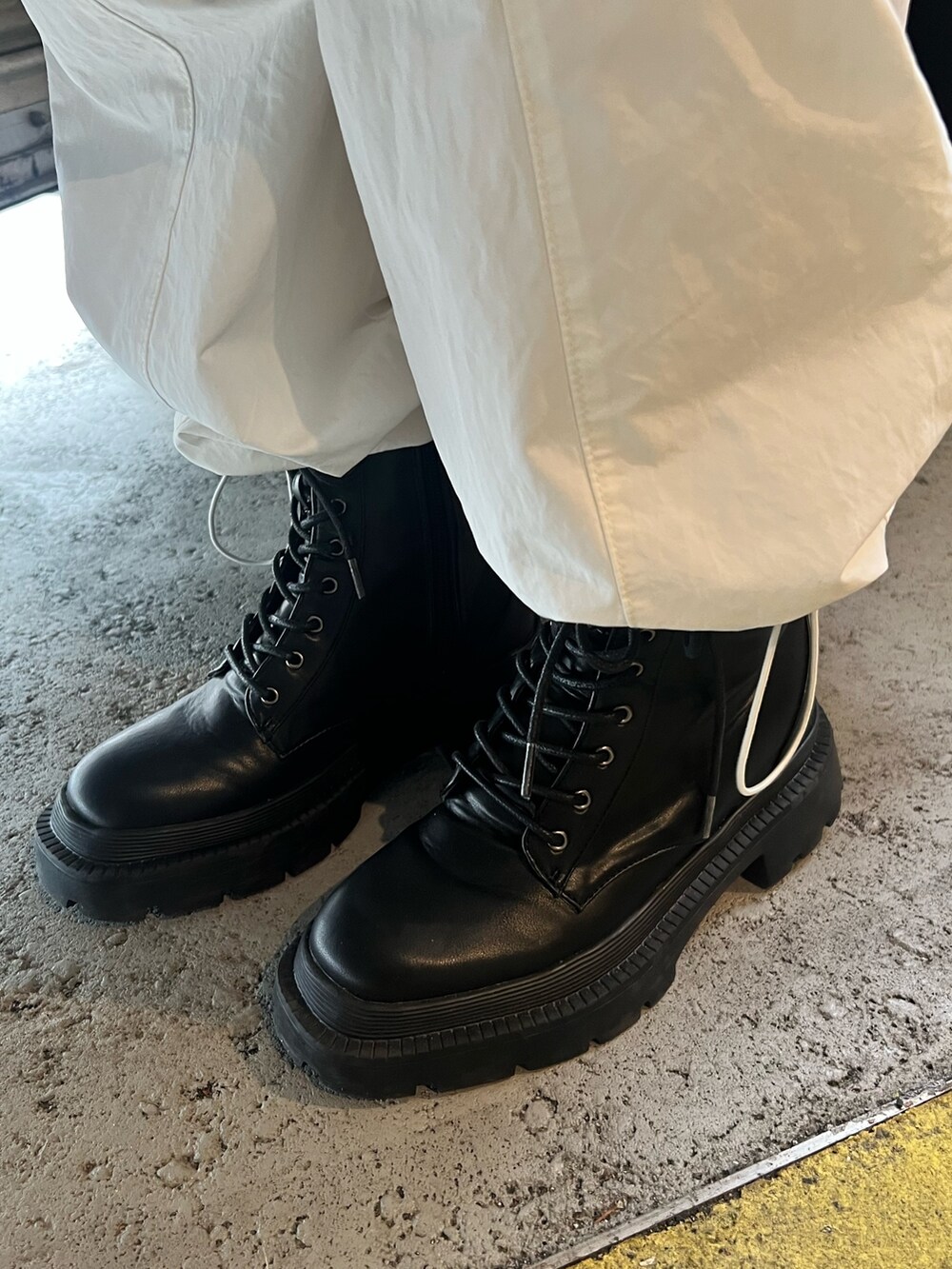 ブラック系のトレンチコート、ホワイト系のカーゴパンツ、ブラック系のショルダーバッグを着用したレディースの春コーディネートの9枚目の写真