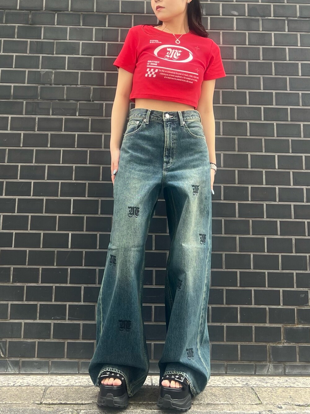 レッド系のTシャツ/カットソー、ブルー系のデニムパンツ、ブラック系のサンダルを着用したレディースの春コーディネートの2枚目の写真