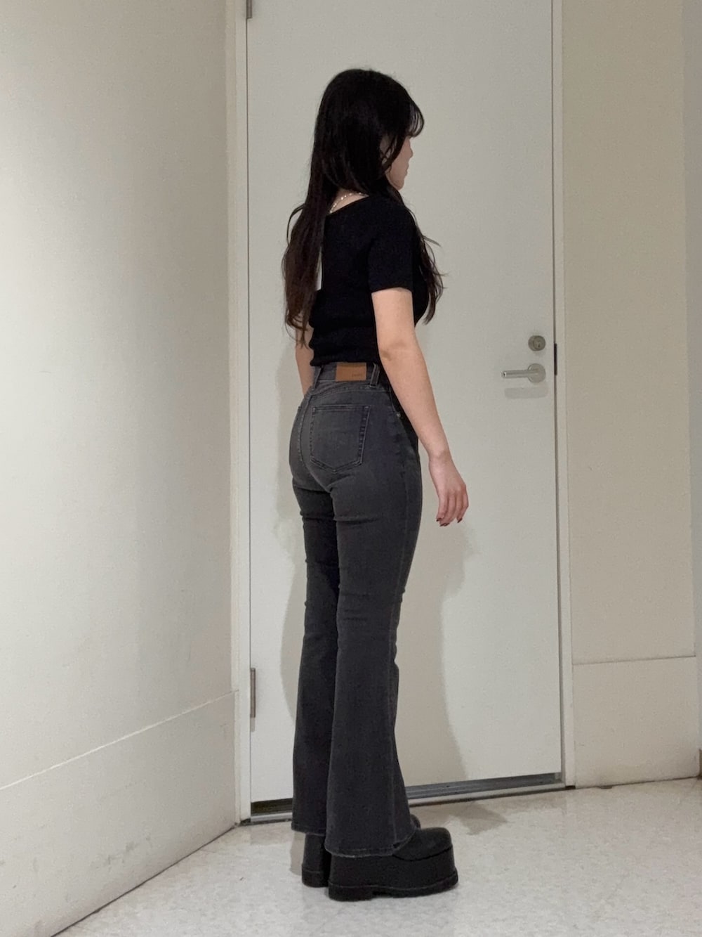 ブラック系のデニムパンツ、ブラック系のブーツ、ブラック系のニット/セーターを着用したレディースの春コーディネートの2枚目の写真