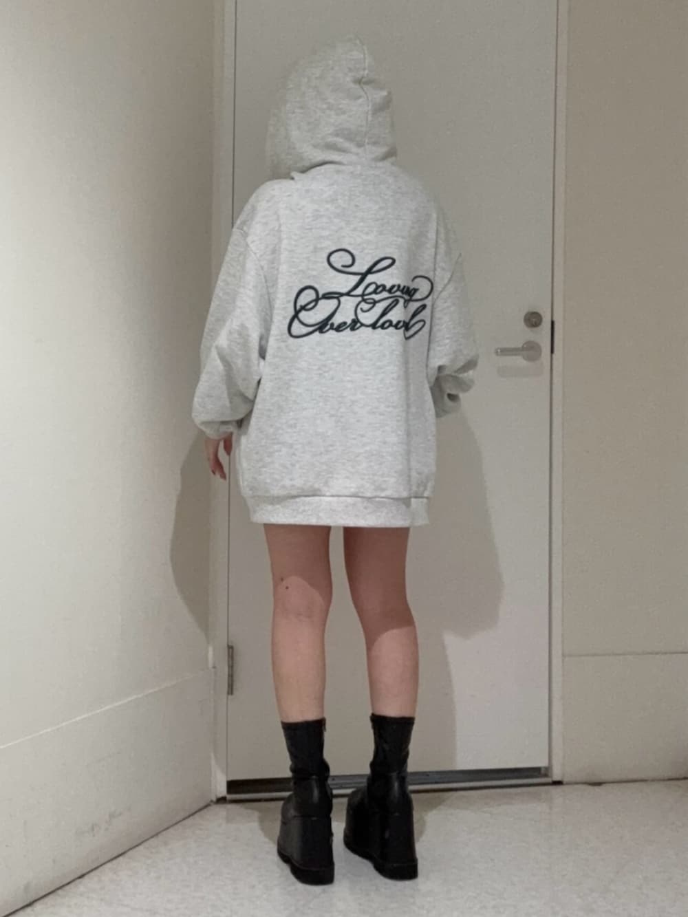 ブラック系のブーツ、グレー系のパーカー、ブラック系のキャップを着用したレディースの春コーディネートの3枚目の写真