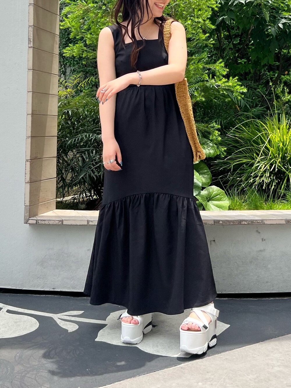 ブラック系のワンピース、ベージュ系のトートバッグ、ホワイト系のサンダルを着用したレディースの夏コーディネートの3枚目の写真