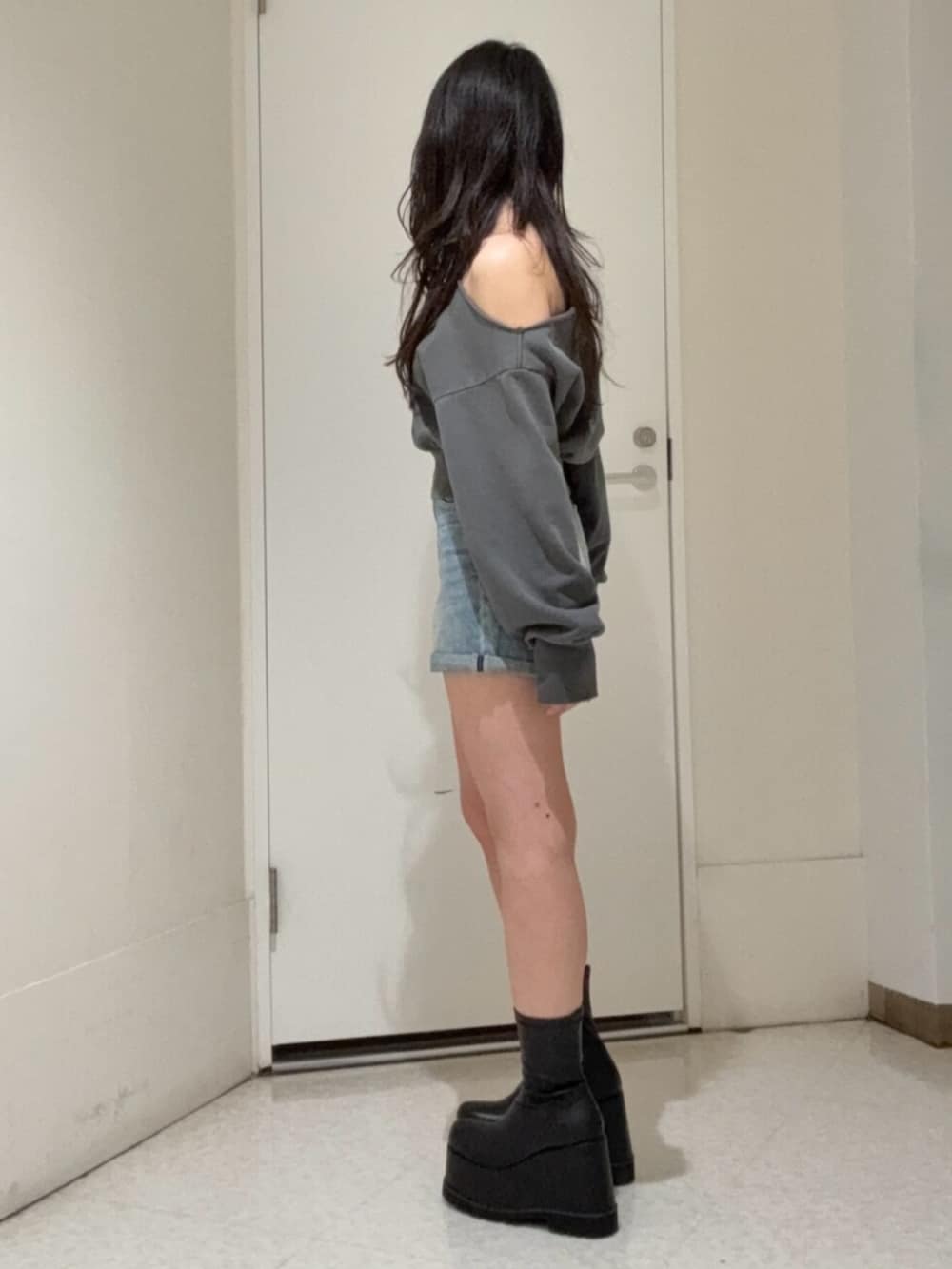 ブラック系のブーツ、ブルー系のデニムパンツ、ブラック系のスウェットを着用したレディースの冬コーディネートの2枚目の写真