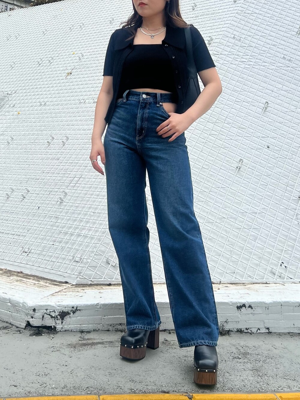 ブルー系のデニムパンツ、ブラック系のニット/セーター、ブラック系のハンドバッグを着用したレディースの春コーディネートの3枚目の写真