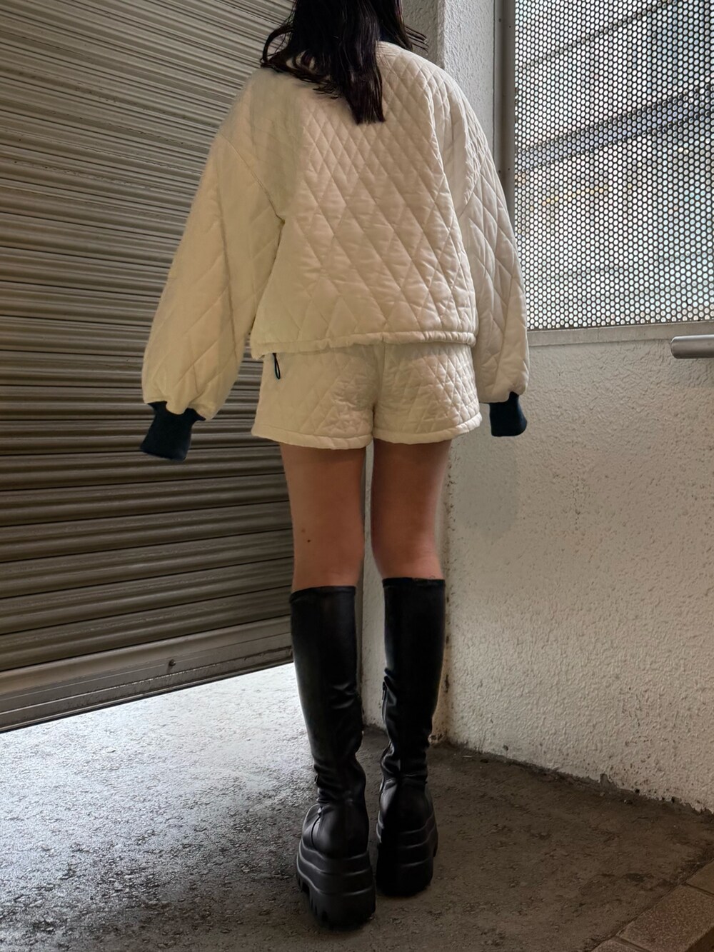 ブラック系のブーツ、ホワイト系のブルゾン、ホワイト系のその他パンツを着用したレディースの冬コーディネートの4枚目の写真