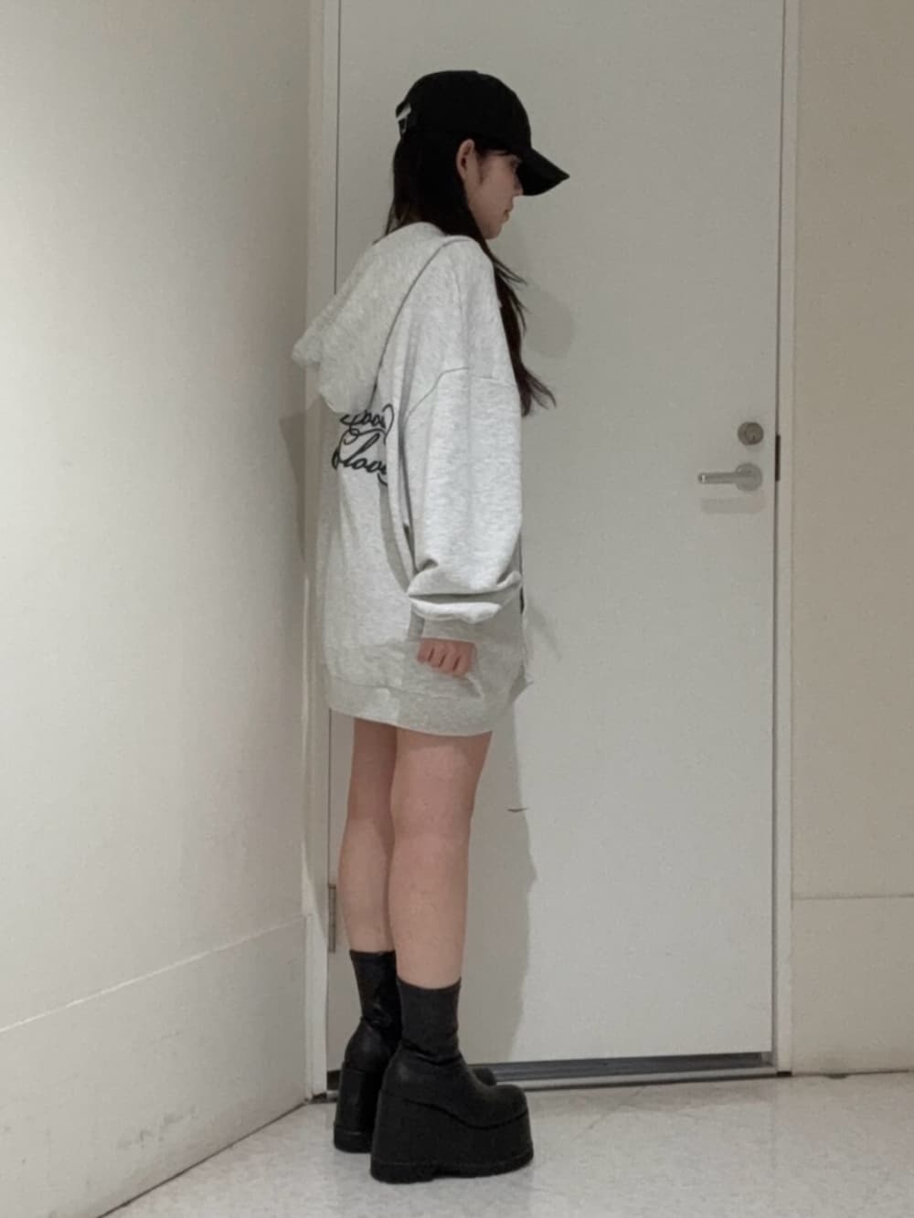 ブラック系のブーツ、グレー系のパーカー、ブラック系のキャップを着用したレディースの春コーディネートの2枚目の写真