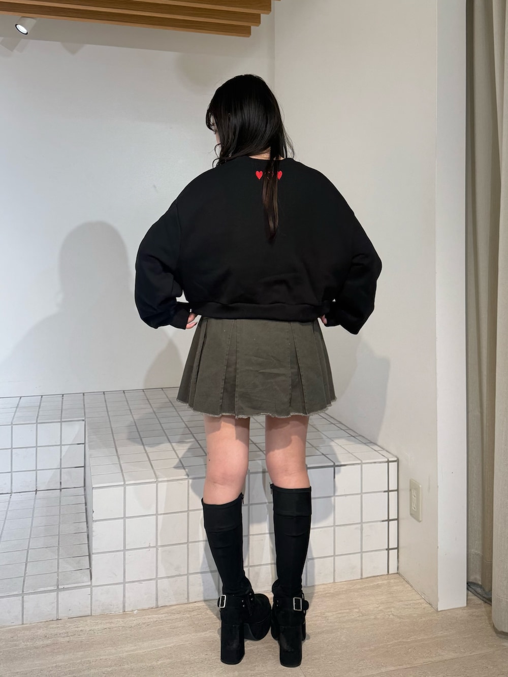 ブラック系のスウェット、ブラック系のブーツ、グレー系のスカートを着用したレディースの秋コーディネートの3枚目の写真