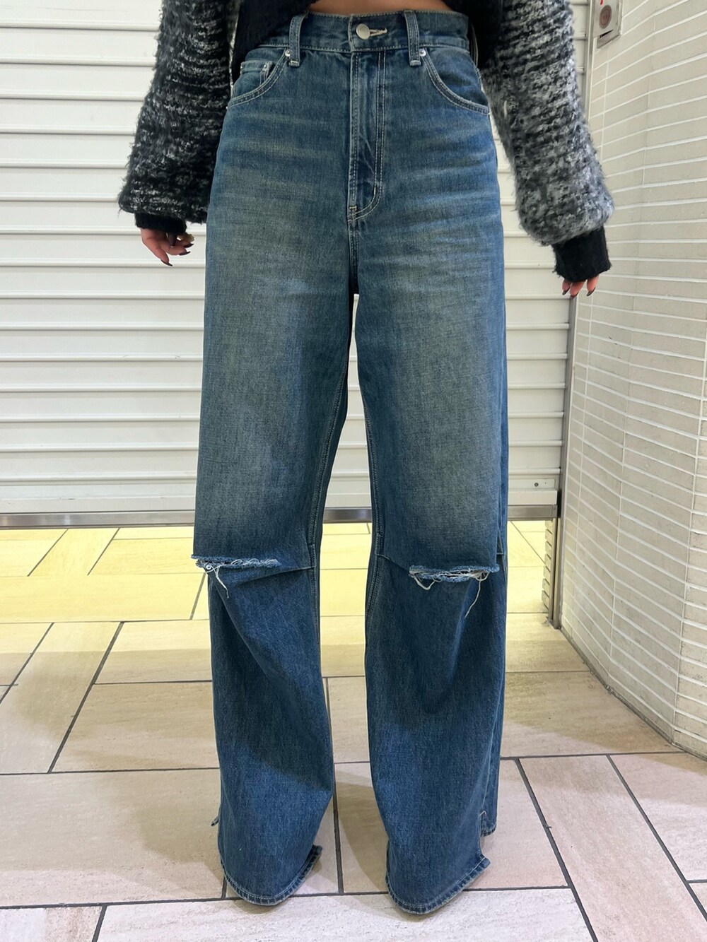 ブルー系のデニムパンツ、ブラック系のカーディガン/ボレロ、ブラック系のブーツを着用したレディースの冬コーディネートの6枚目の写真