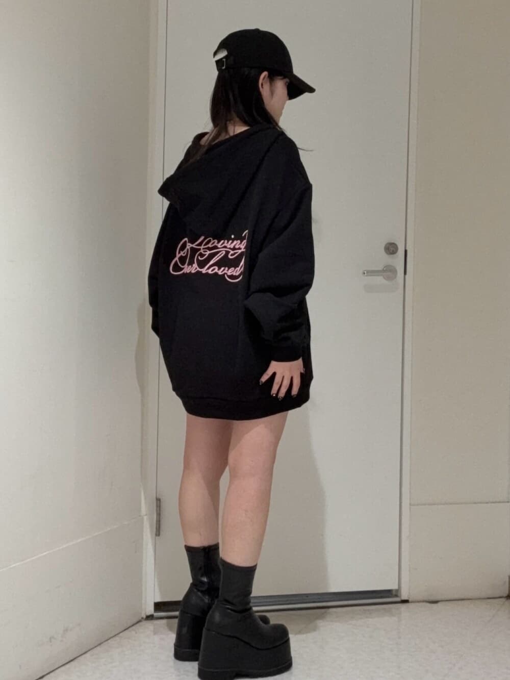 ブラック系のブーツ、ブラック系のパーカー、ブラック系のキャップを着用したレディースの春コーディネートの2枚目の写真