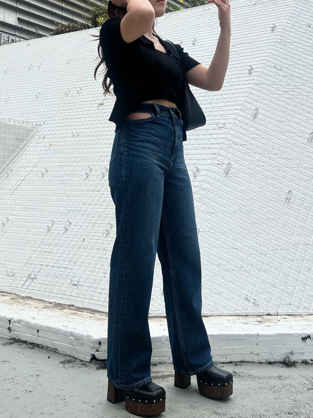 ブルー系のデニムパンツ、ブラック系のニット/セーター、ブラック系のハンドバッグを着用したレディースの春コーディネートの4枚目の写真