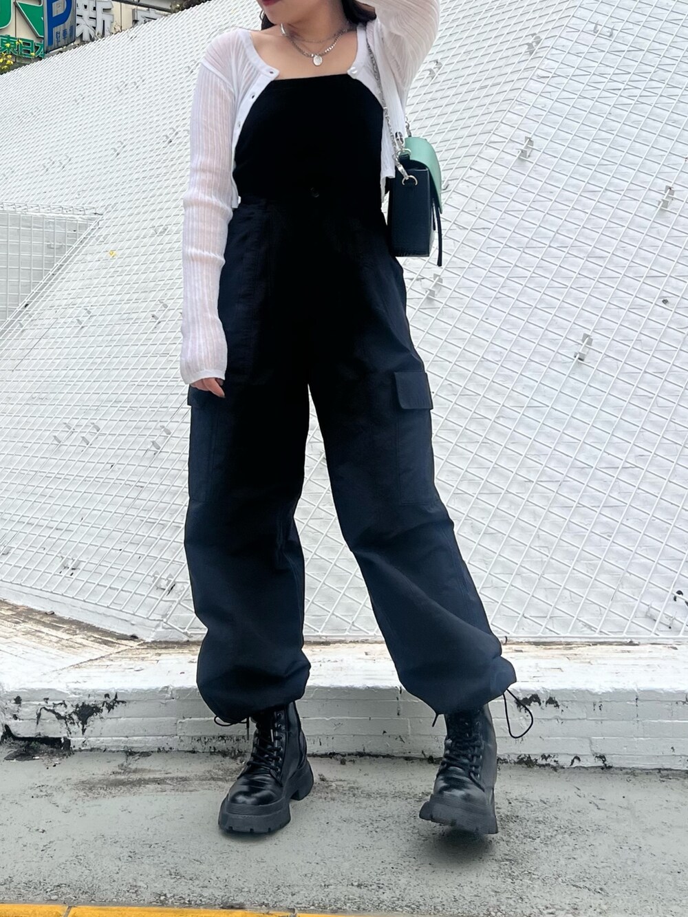 ブラック系のカーゴパンツ、ブラック系のブーツ、ホワイト系のカーディガン/ボレロを着用したレディースの春コーディネートの4枚目の写真