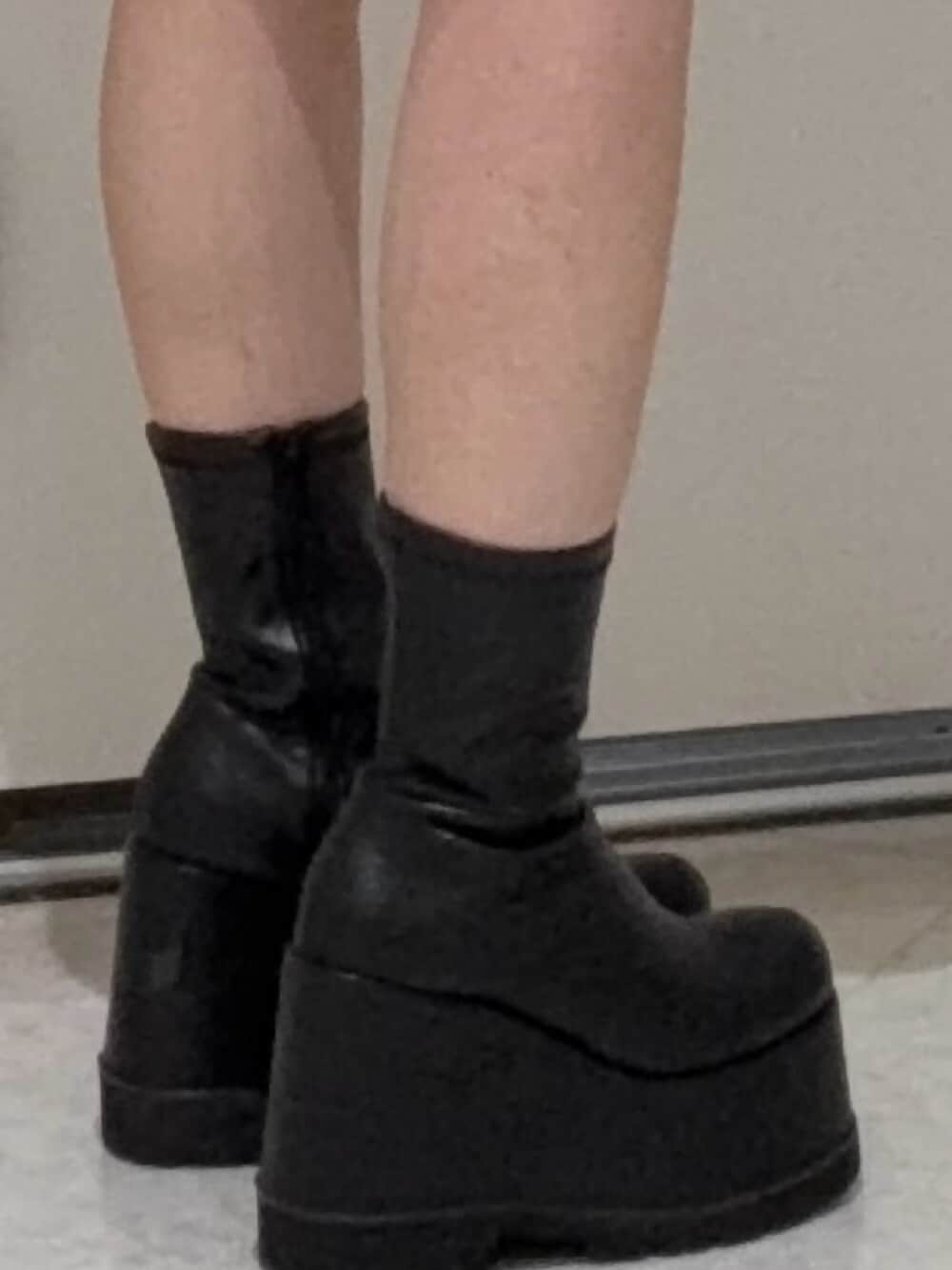 ブラック系のブーツ、グレー系のパーカー、ブラック系のキャップを着用したレディースの春コーディネートの5枚目の写真