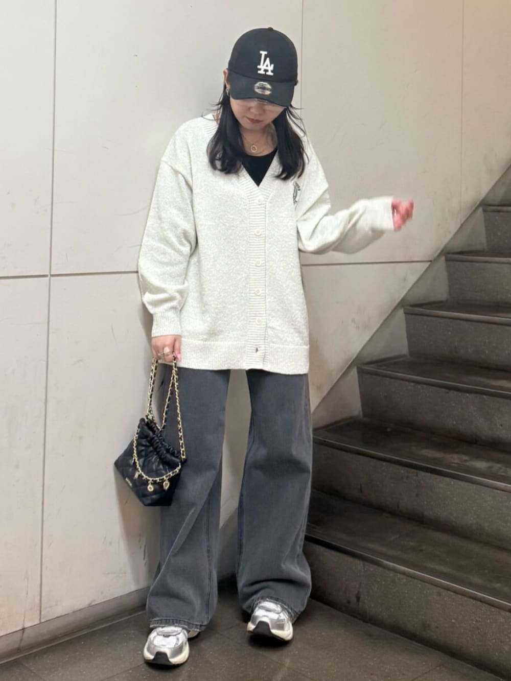 グレー系のニット/セーター、ホワイト系のカーディガン/ボレロ、ブラック系のデニムパンツを着用したレディースの春コーディネートの2枚目の写真