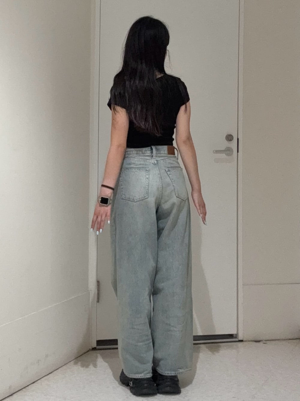 ブラック系のTシャツ/カットソー、ブルー系のデニムパンツ、ブラック系のサンダルを着用したレディースの春コーディネートの3枚目の写真