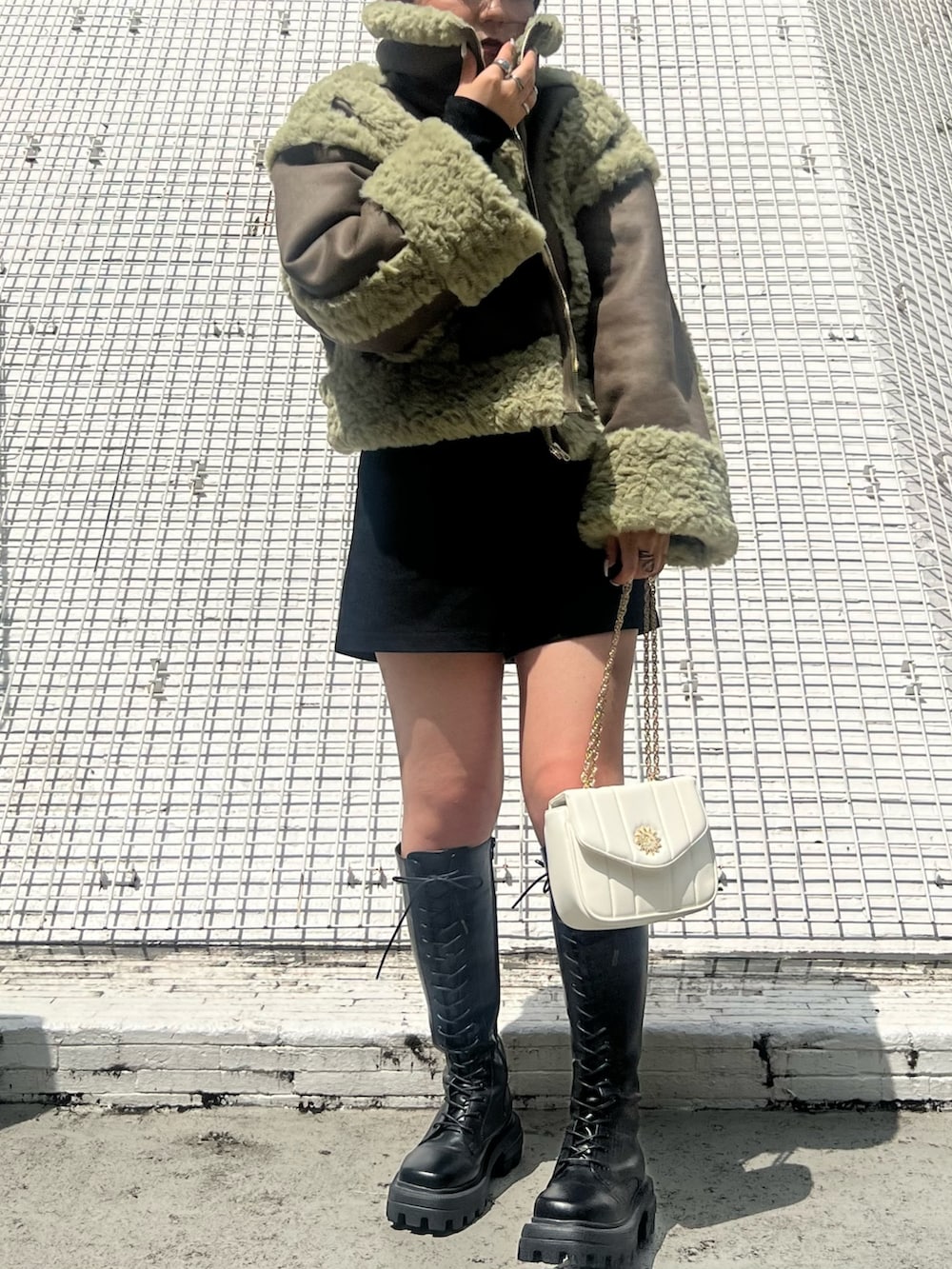 ブラック系のその他パンツ、ブラック系のブーツ、グリーン系のムートンコートを着用したレディースの夏コーディネートの4枚目の写真